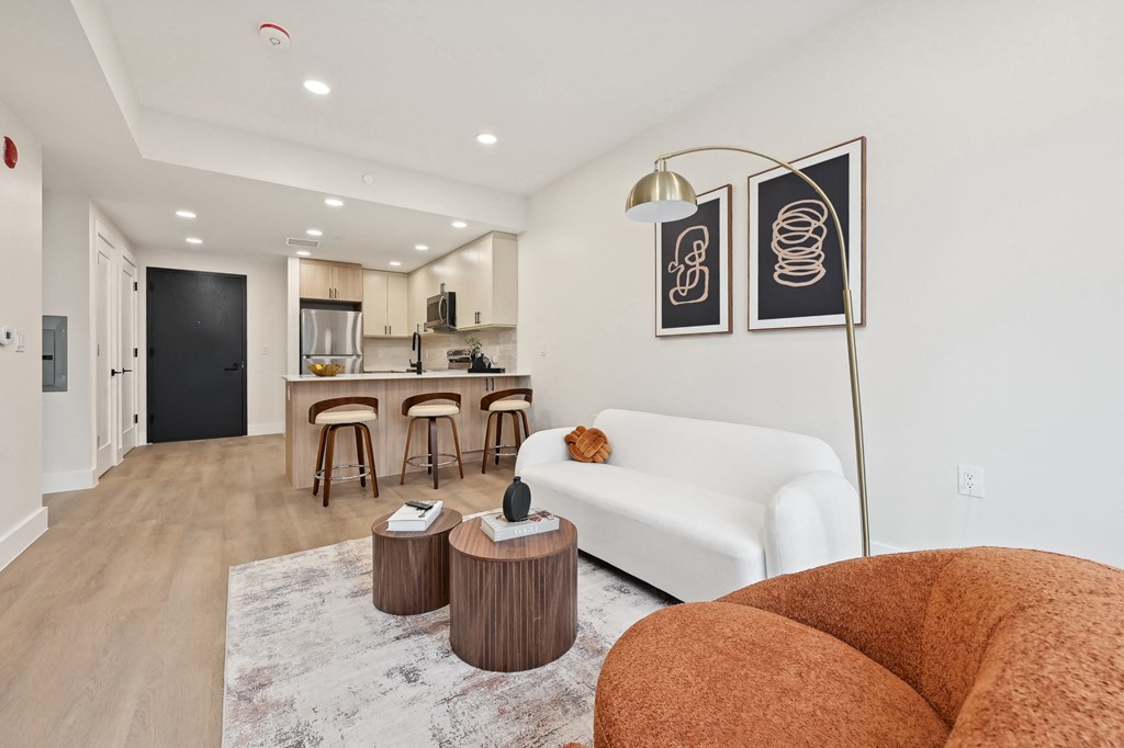 a living room with a white couch and a kitchen in the background