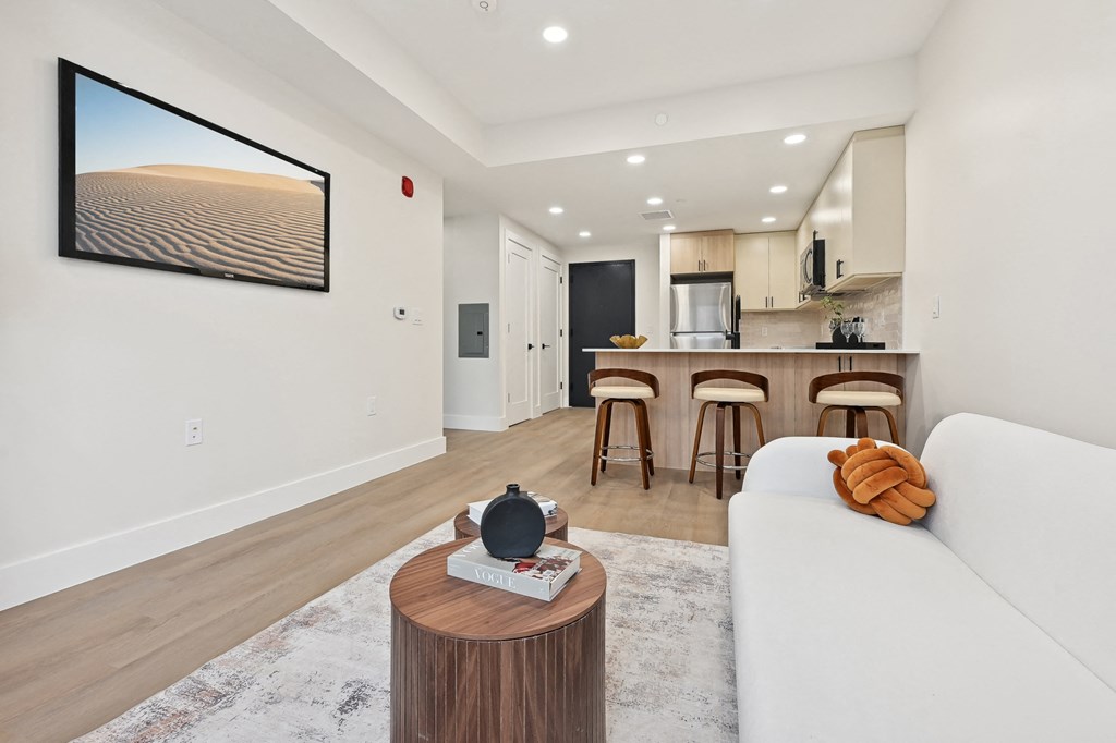 a living room with a couch and a table in front of a kitchen