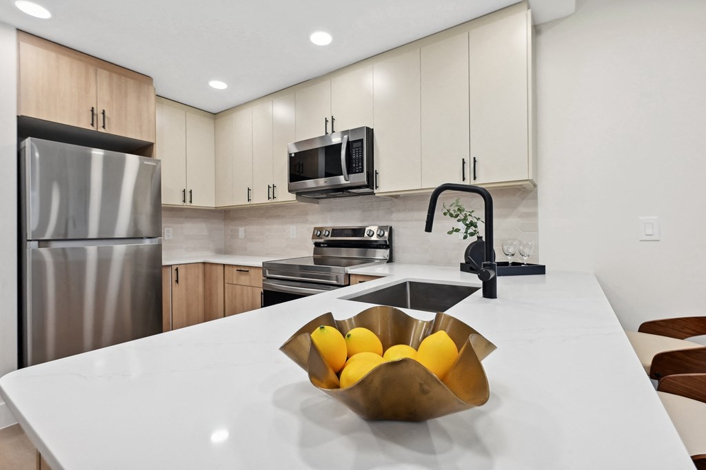 a kitchen with stainless steel appliances and a counter with a bowl of fruit