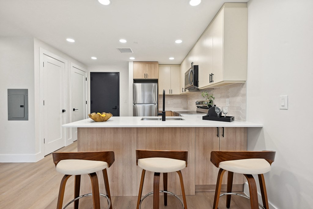 a white kitchen with three wooden stools in front of a counter top