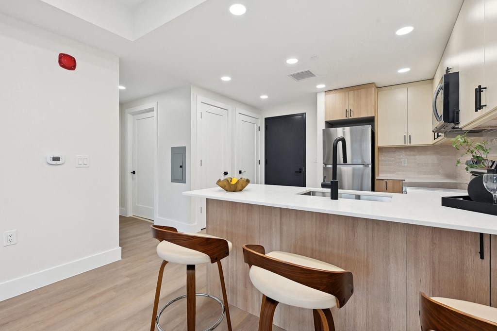 a kitchen with a white counter top and wooden stools