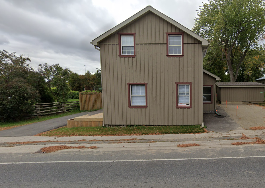 A two-story house with a brown siding and red window frames.