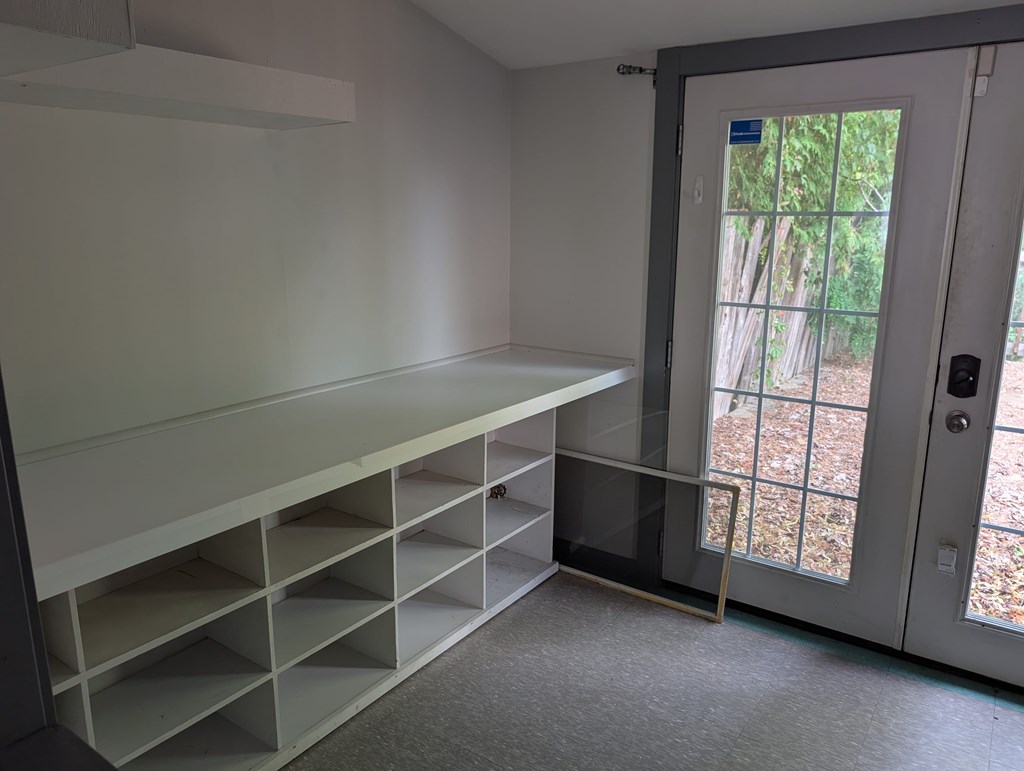 A white shelving unit in a room with a glass door leading outside.