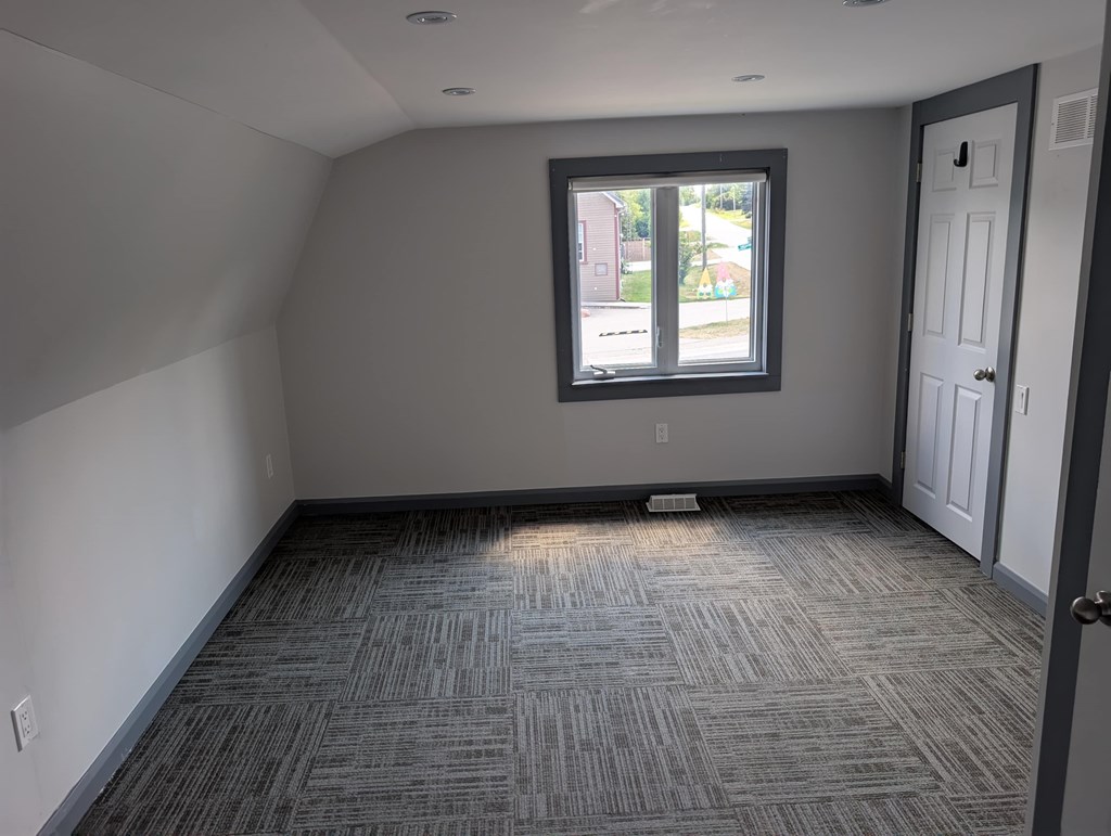 A room with a carpeted floor and a window.