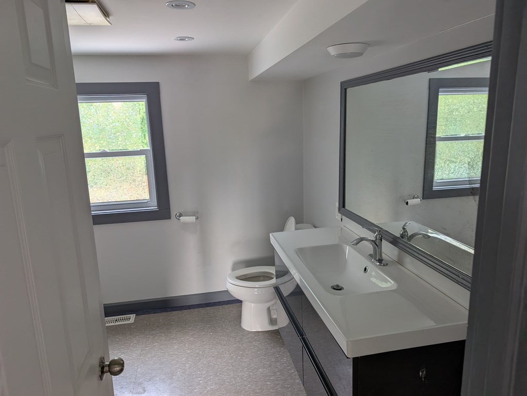 A bathroom with a toilet, sink, and mirror.