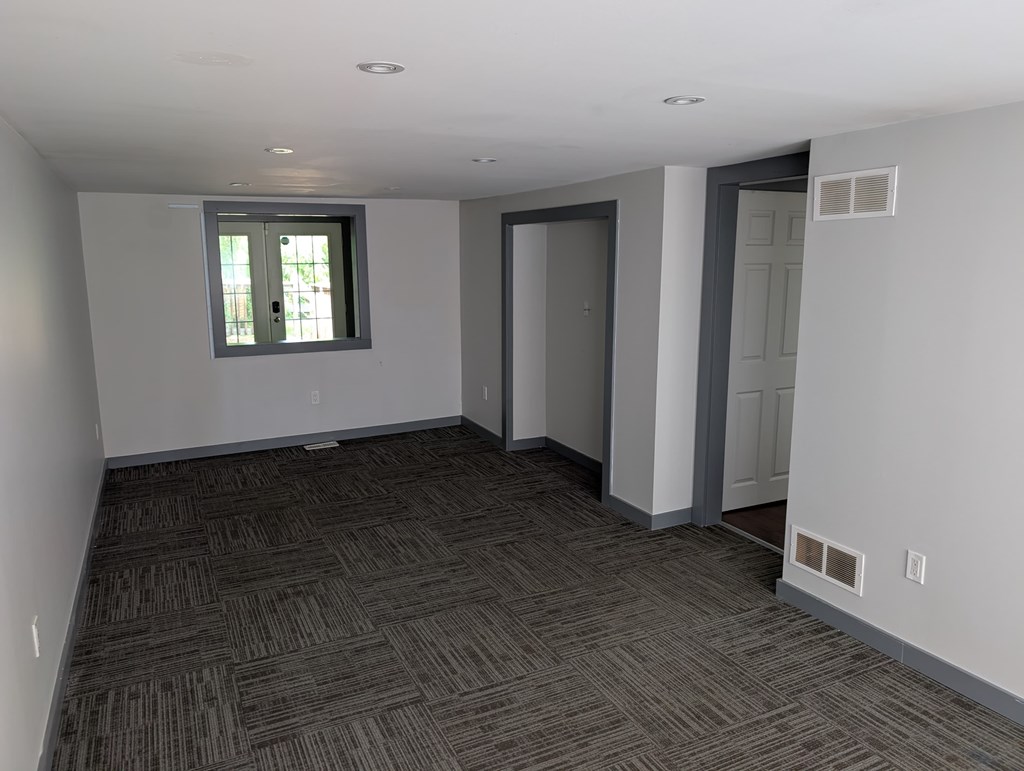 A room with a carpeted floor and a window.