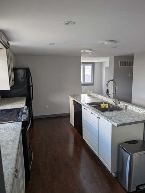 A kitchen with a sink, stove, and cabinets.