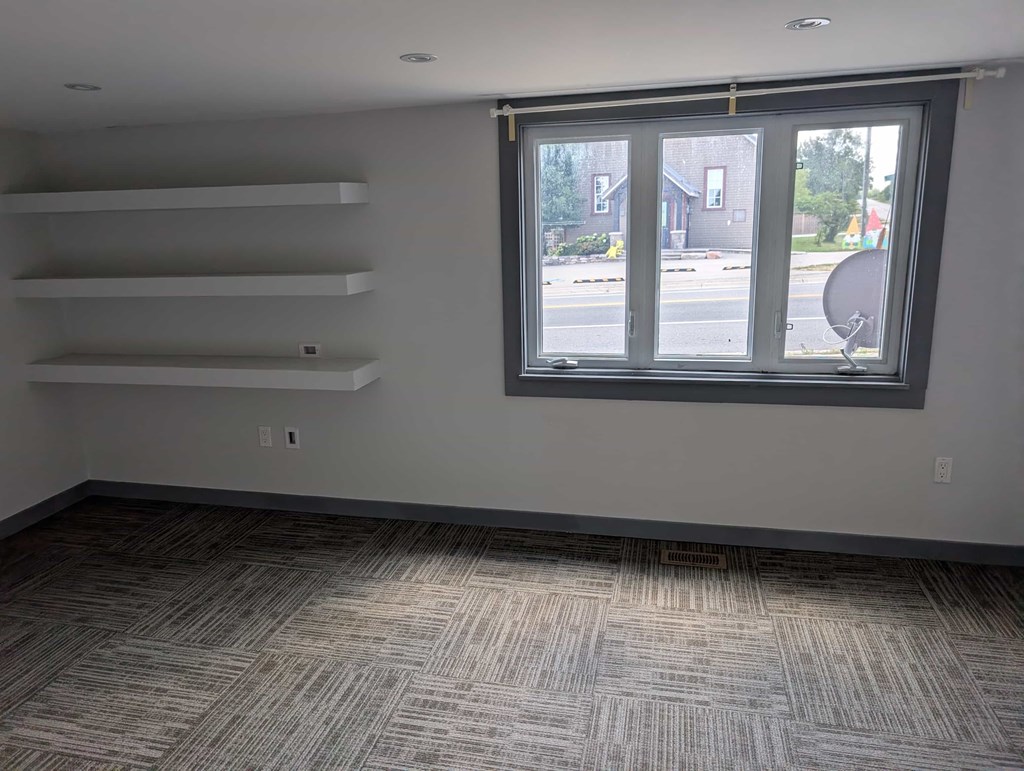 A room with a window and a carpeted floor.