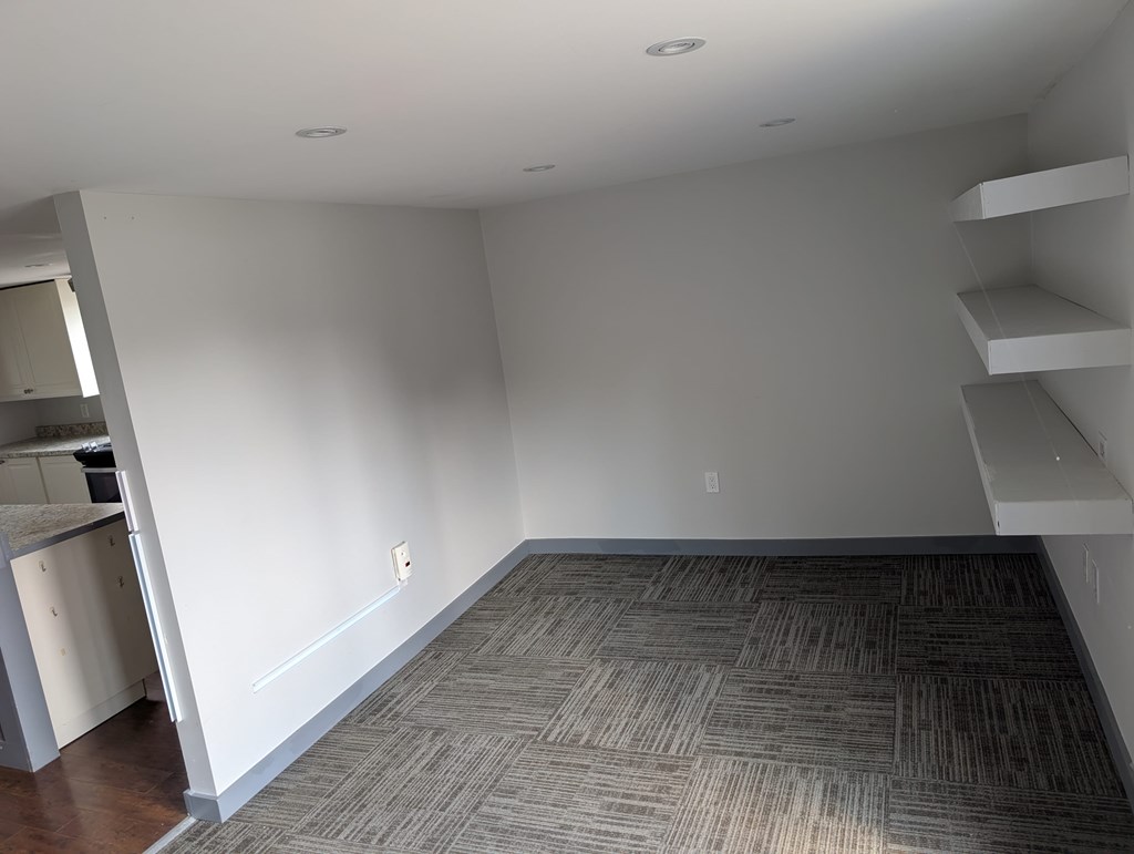 A room with a carpeted floor and a white wall.