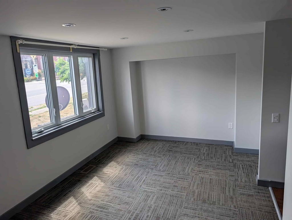 A room with a carpeted floor and a window.
