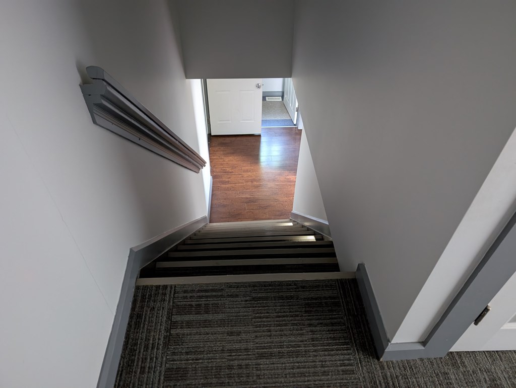 A stairway with a carpeted floor and a metal handrail.