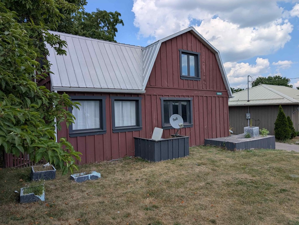 A red barn with a grey roof and a satellite dish on the side.