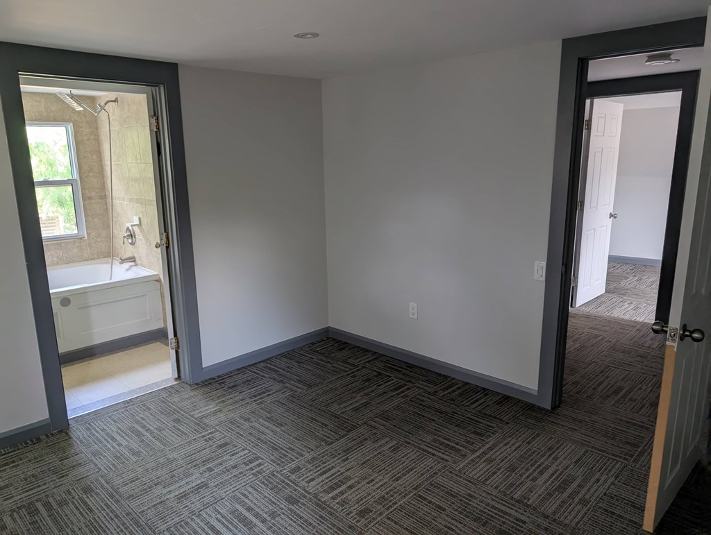 A room with a carpeted floor and a door leading to another room.