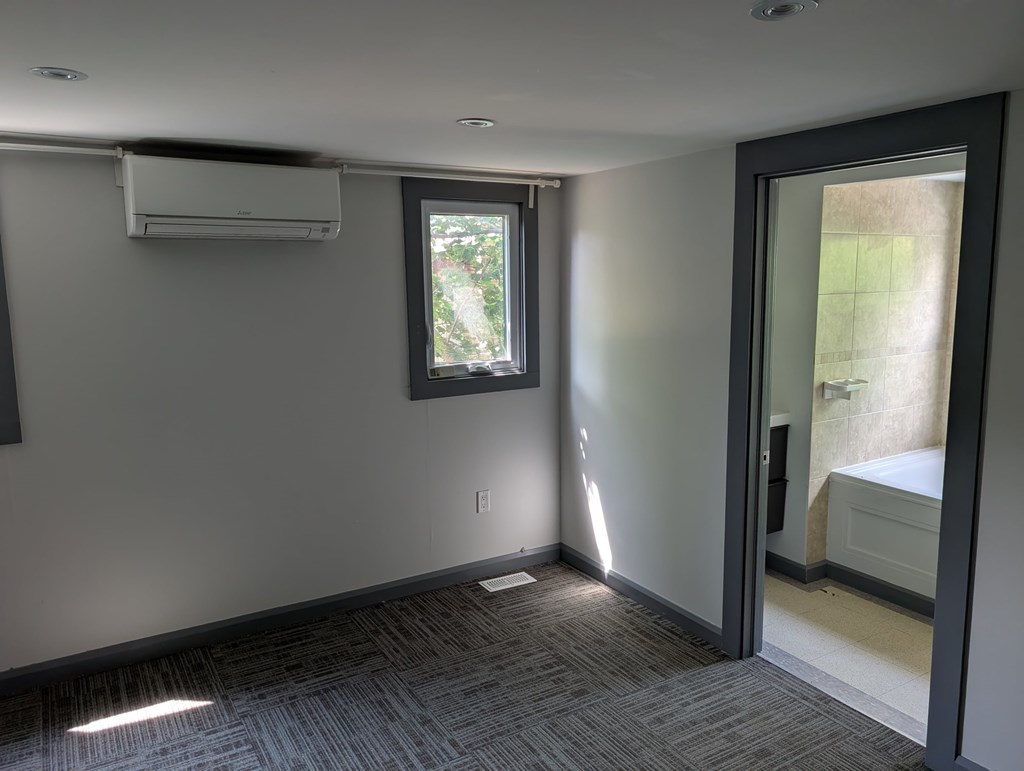 A room with a window and a door leading to a bathroom.