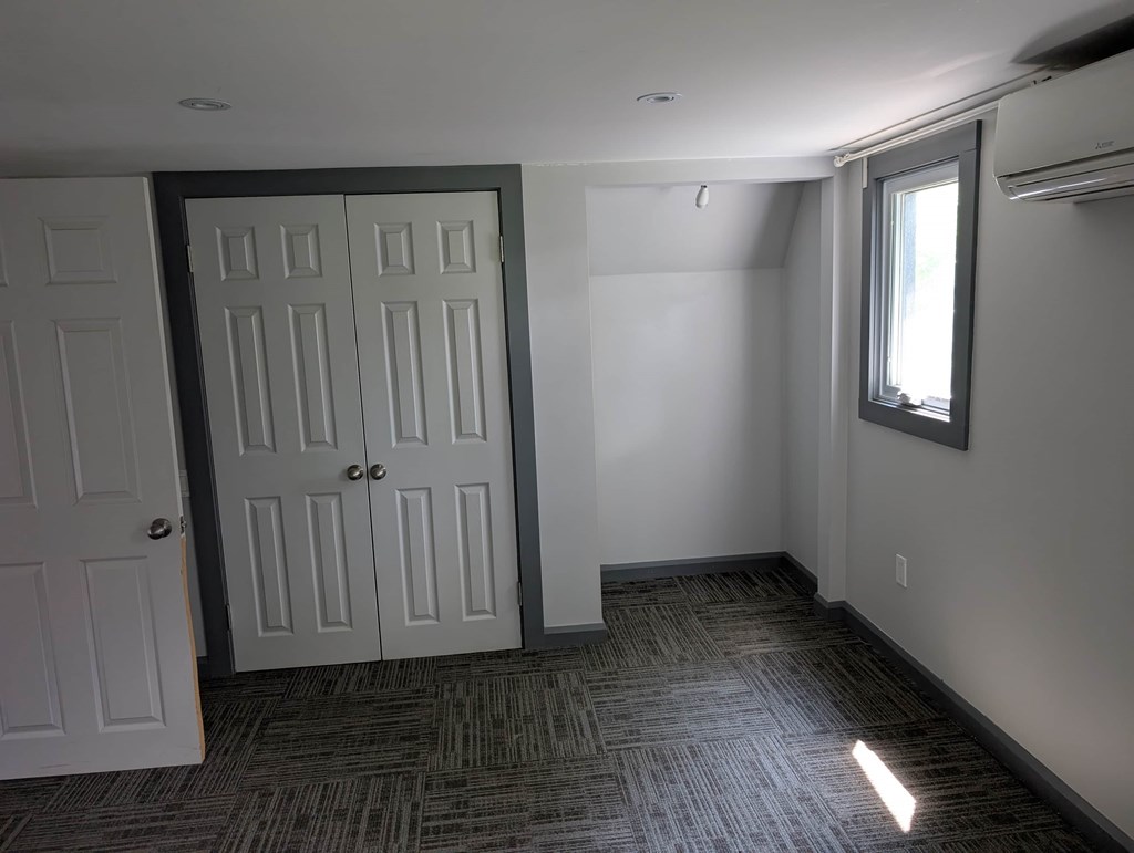 A room with a carpeted floor and a door on the left.