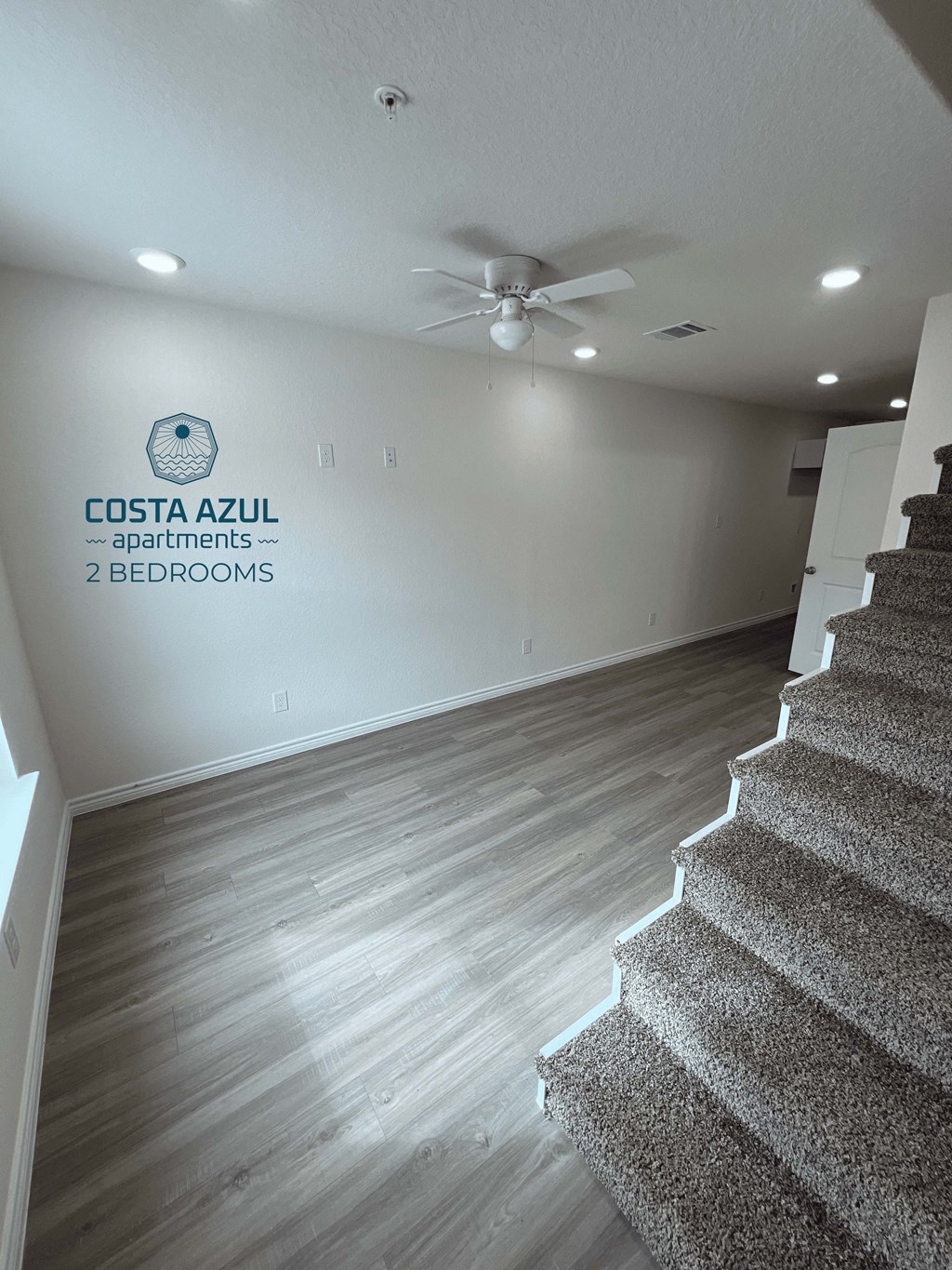 a living room with a staircase and a ceiling fan