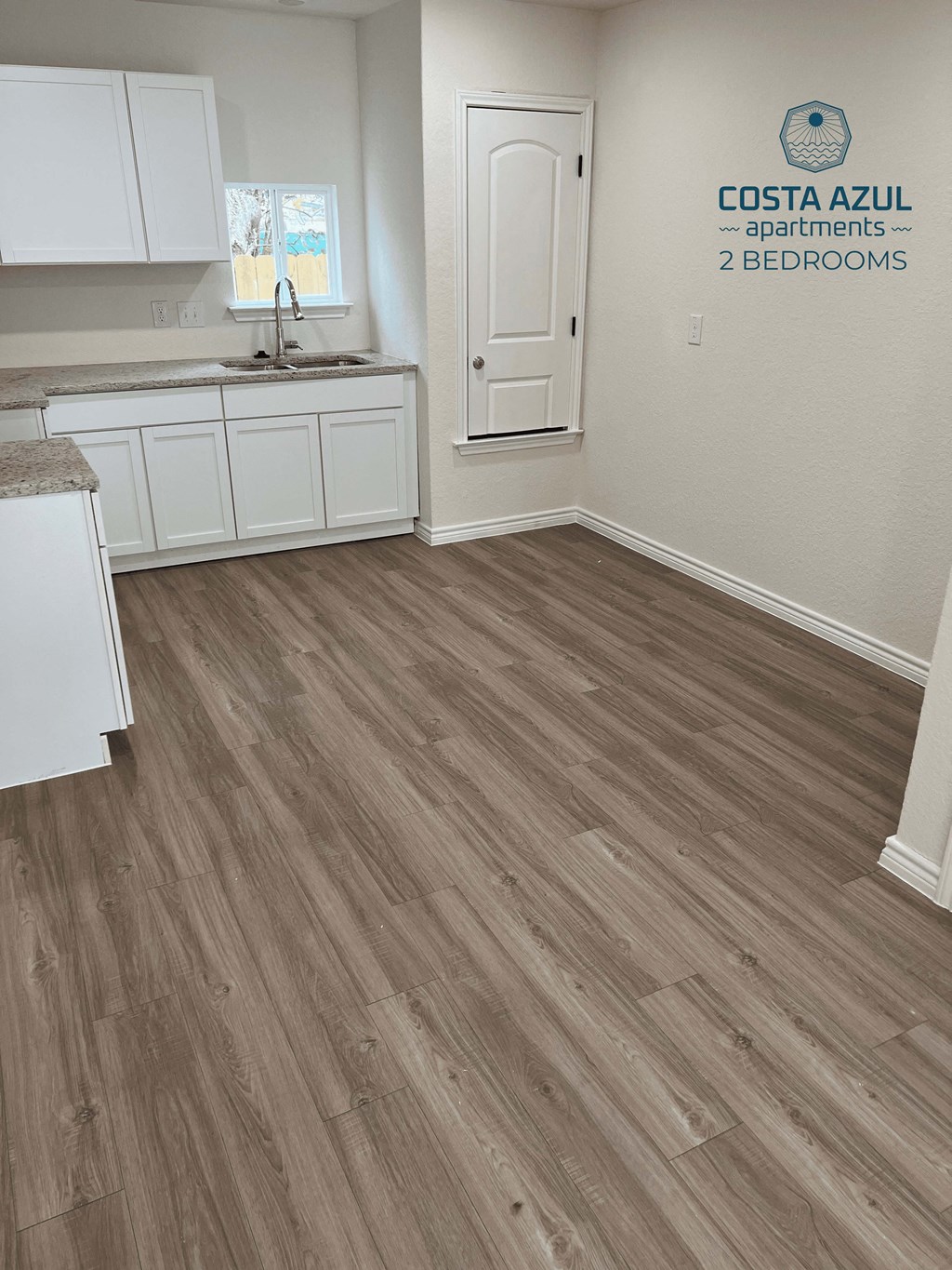 a renovated kitchen with a wooden floor and white cabinets