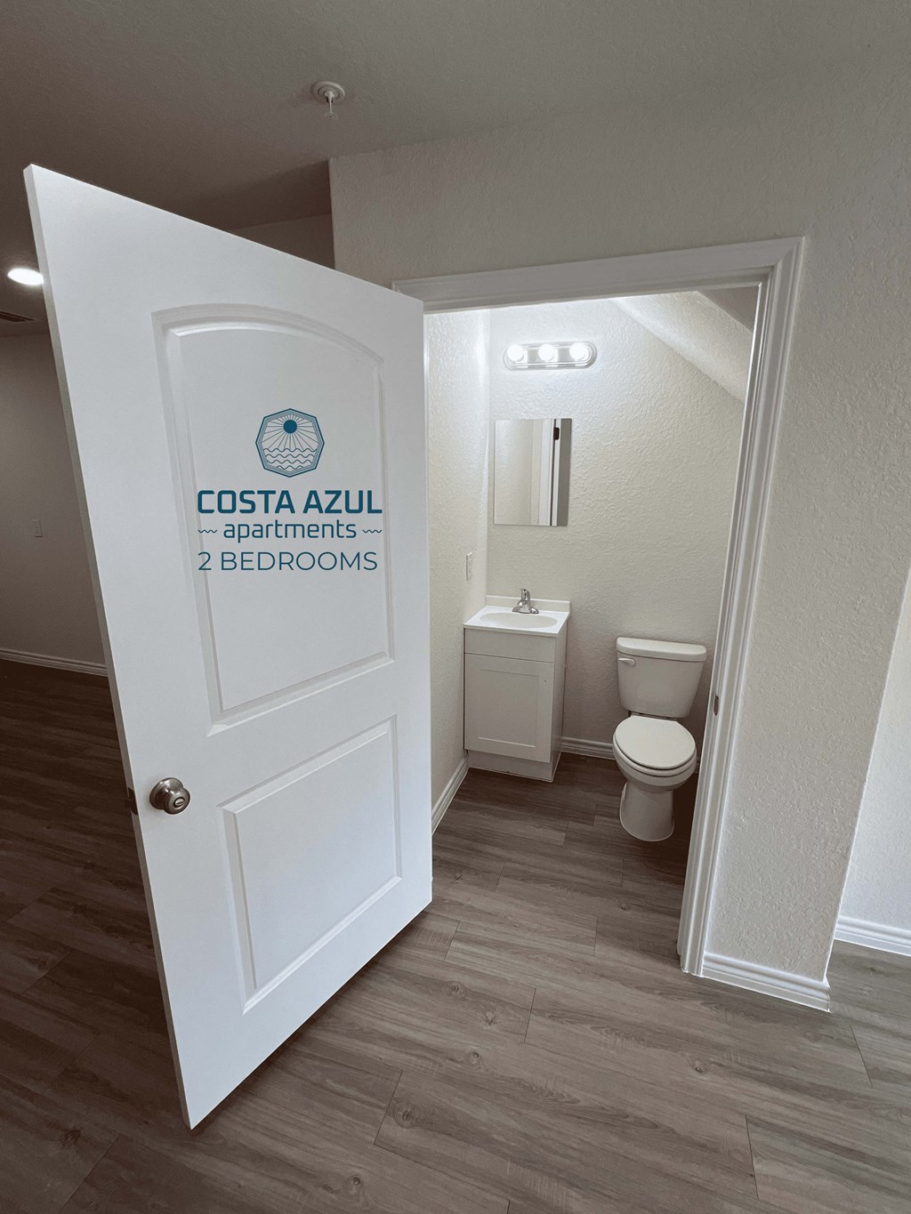 a door leading into a bathroom with a toilet and a sink