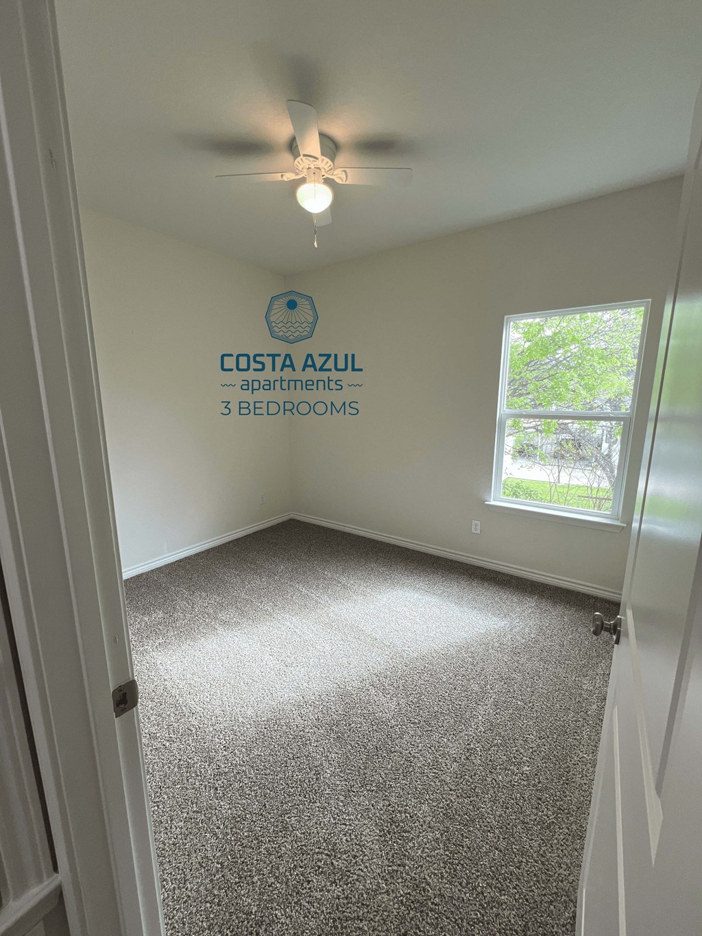 an empty room with a ceiling fan and a window