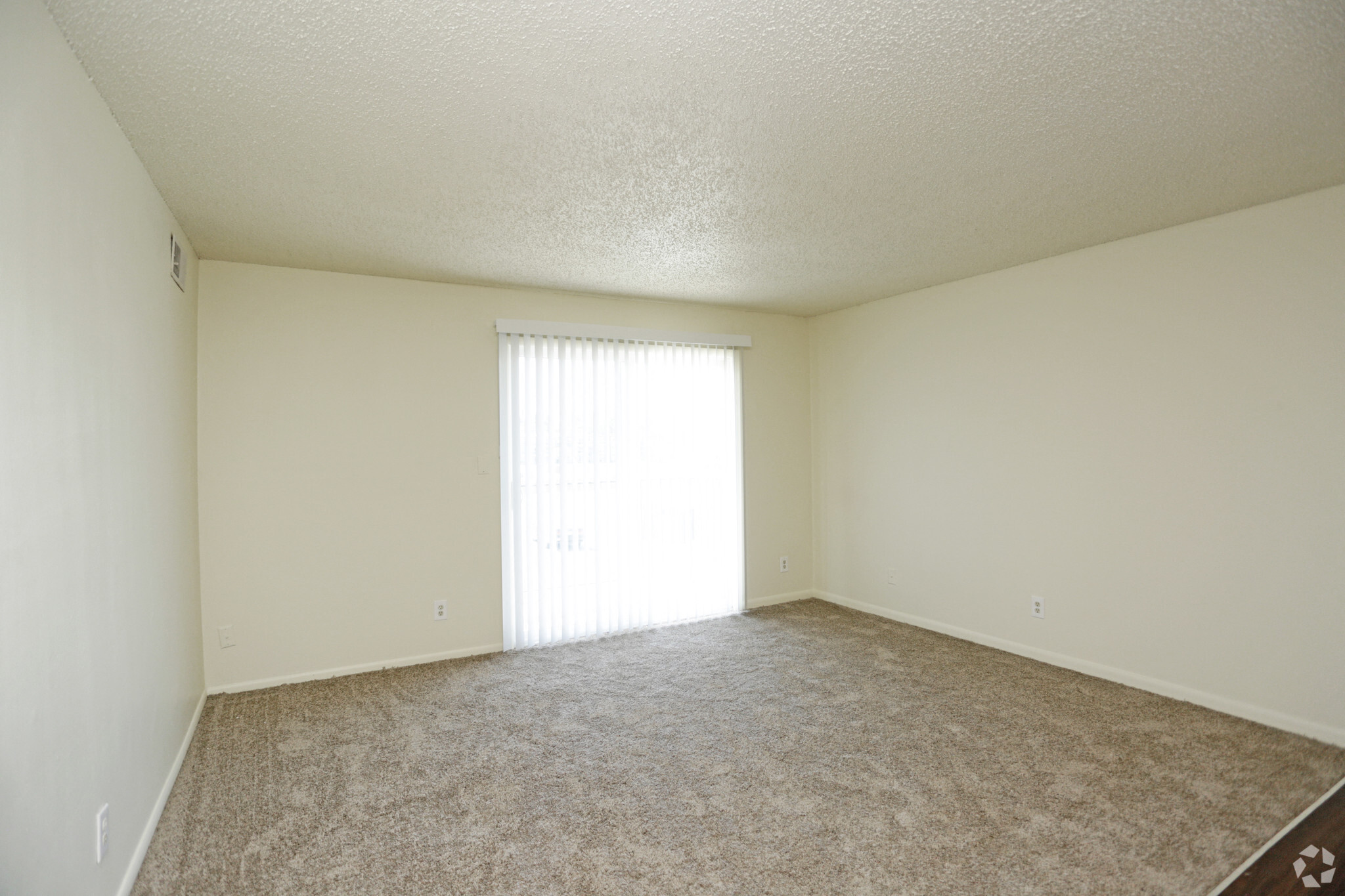 a spacious living room with carpet and a window