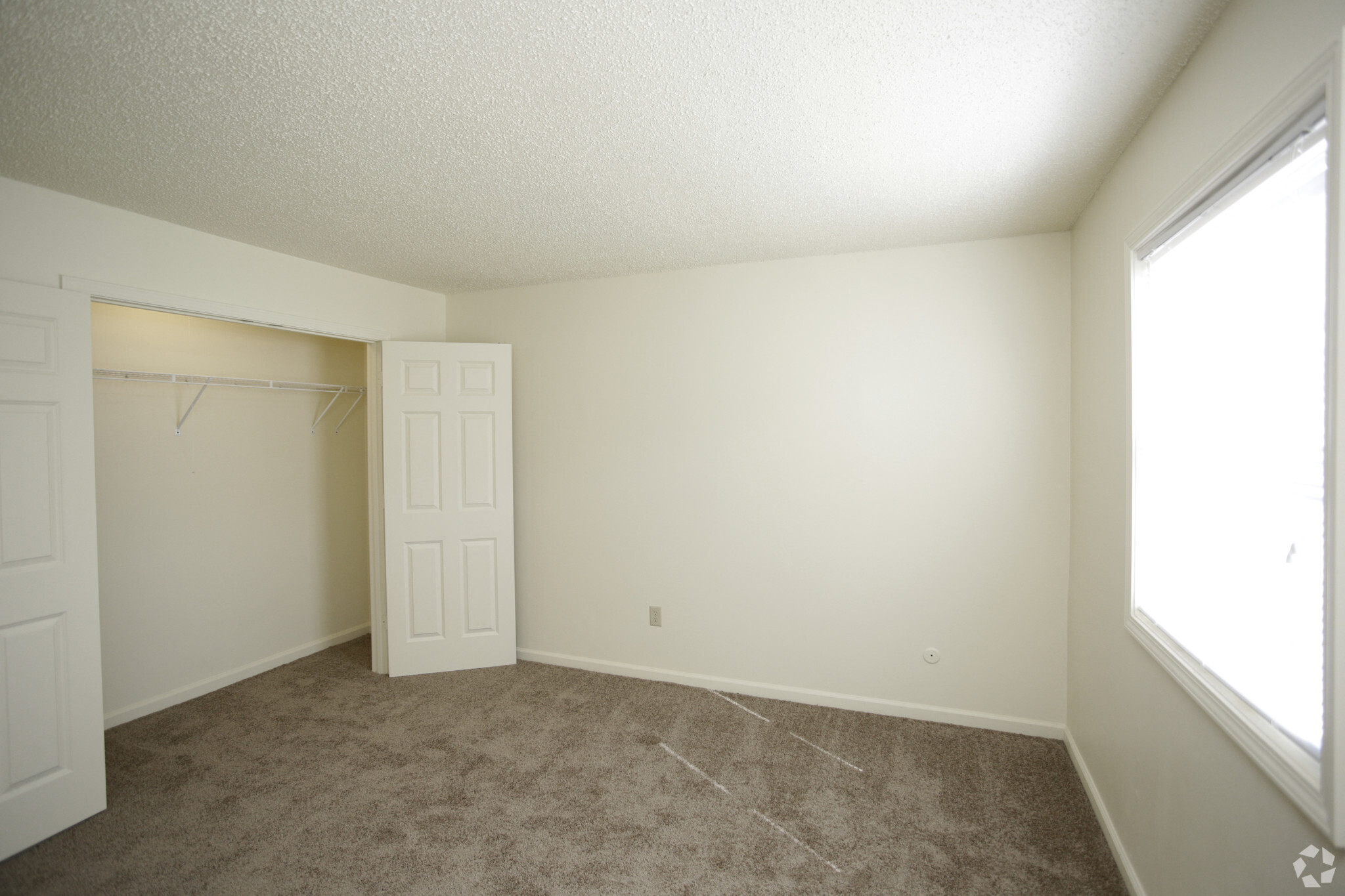 Large carpeted bedroom with large closet and window with blinds