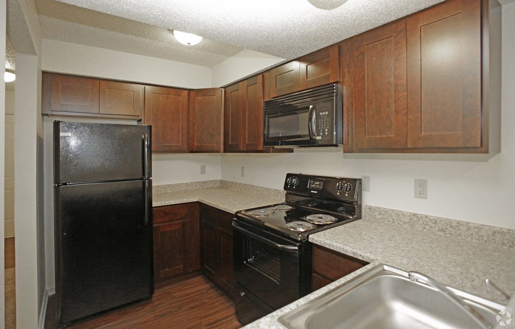 a kitchen with black appliances and granite counter tops and wooden cabinets