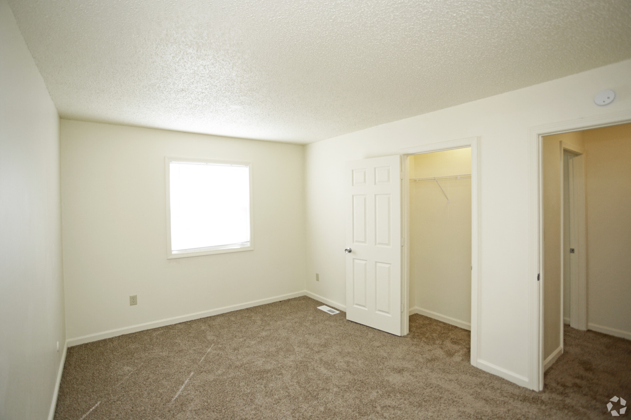 carpeted bedroom with white walls and a window with shades