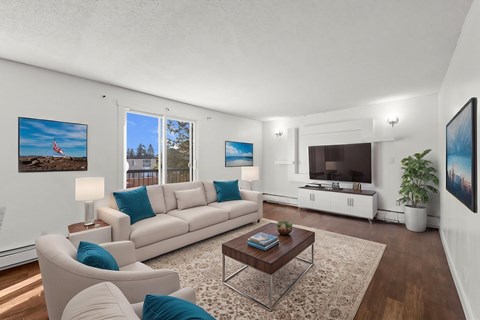 A living room with a white couch, a coffee table, and a large window.