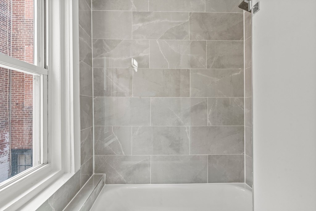A bathroom with a tiled shower and a window.