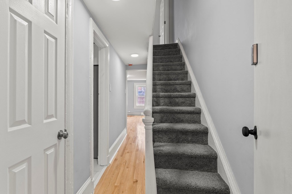 A staircase with a grey carpeted runner and white balusters.
