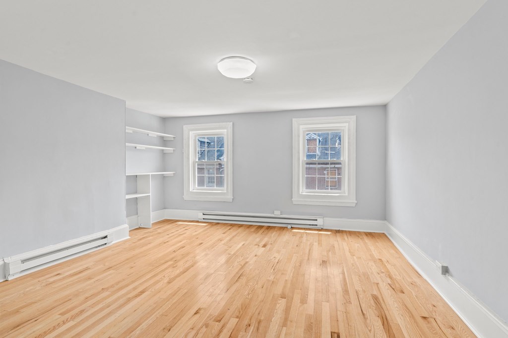 A room with wooden floors and two windows.