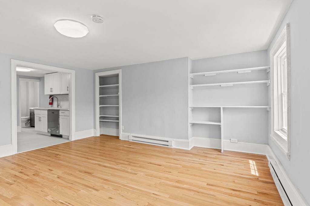A room with white walls and wooden flooring with a large open doorway.