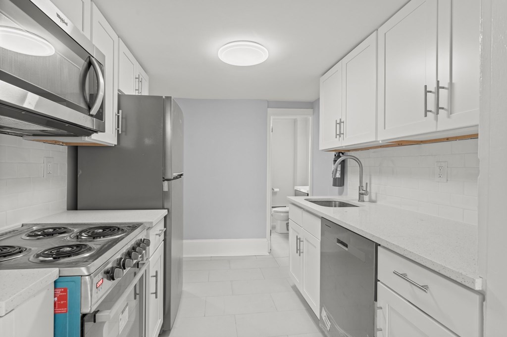 A modern kitchen with white cabinets and stainless steel appliances.