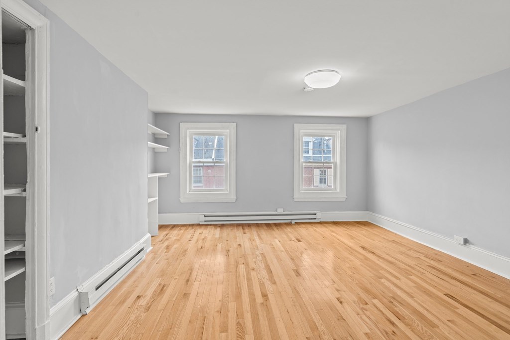 A room with wooden floors and two windows.