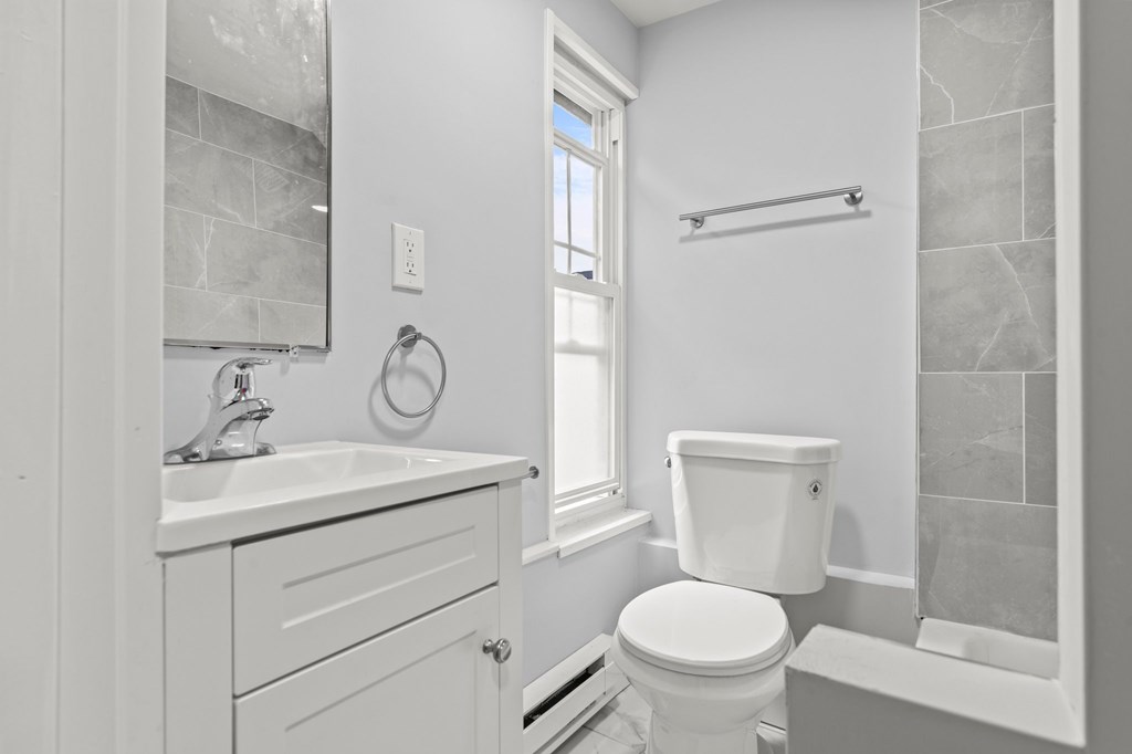 A white bathroom with a toilet, sink, and a window.