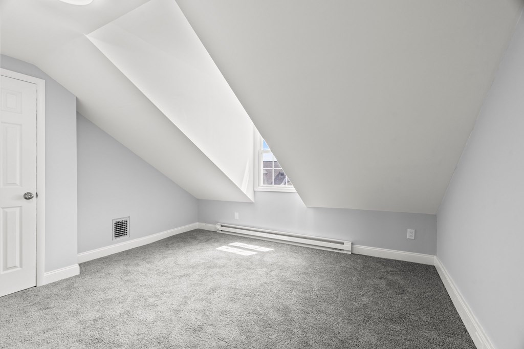 A room with a carpeted floor and a window letting in natural light.