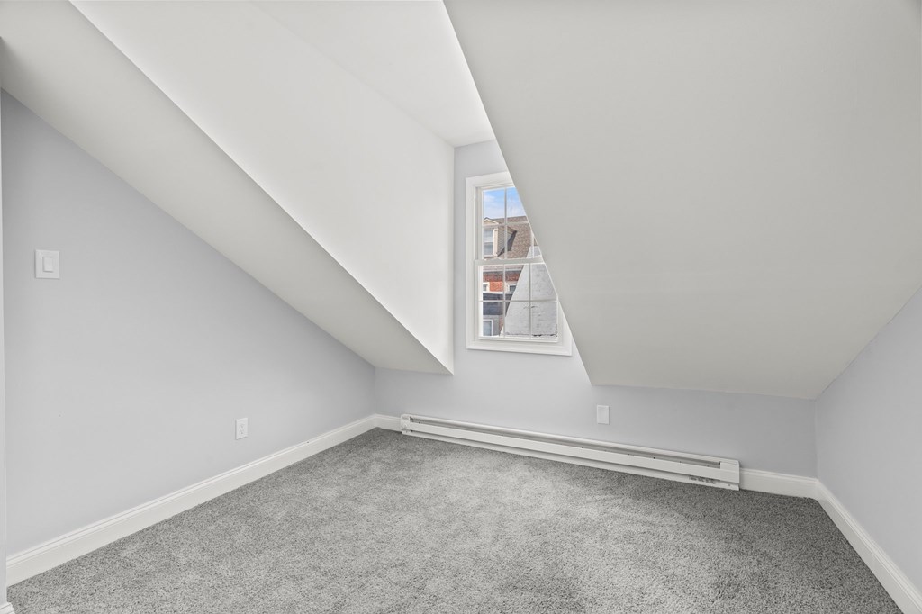 A room with a window and a carpeted floor.