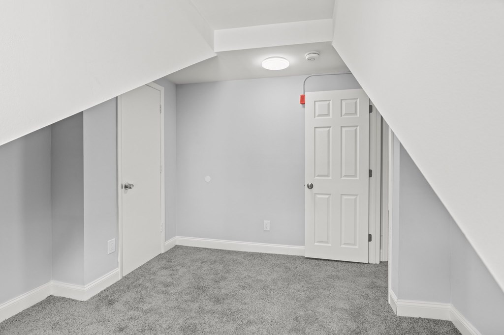A white door is in a white room with a carpet.