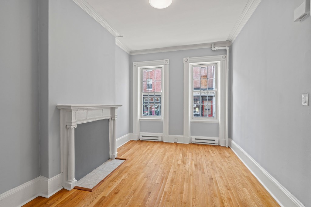 A room with a fireplace and two windows.