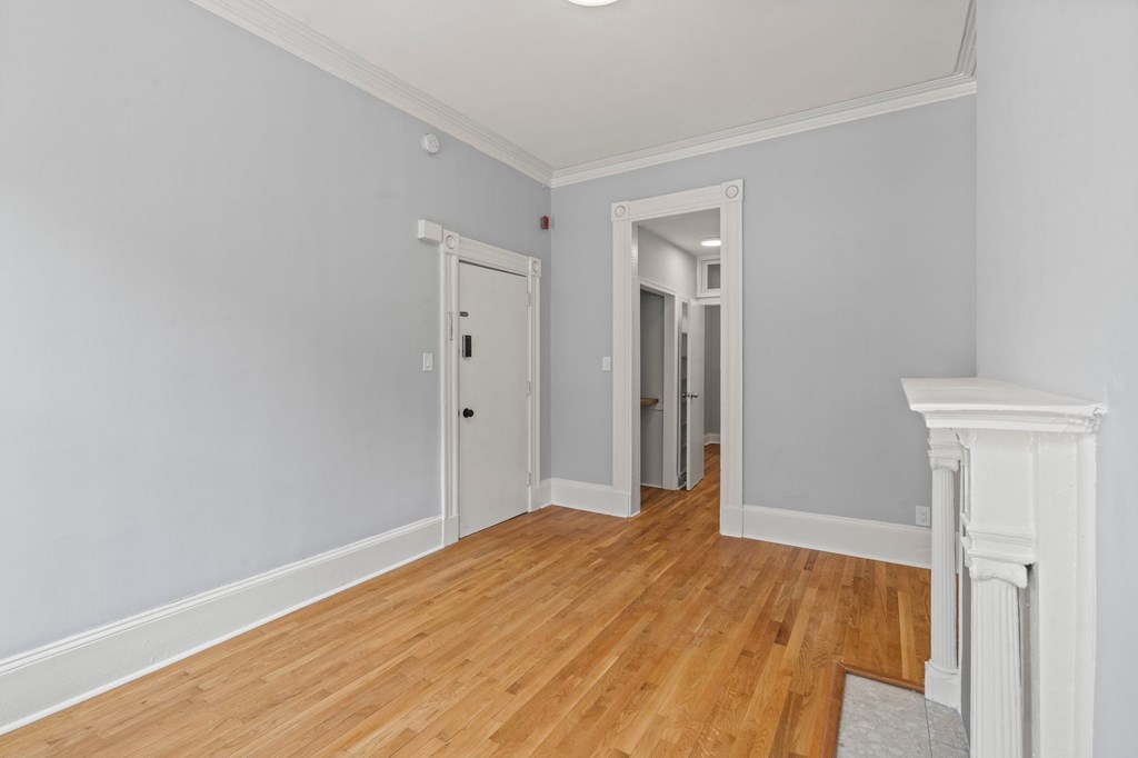 A room with a white fireplace and wooden floors.