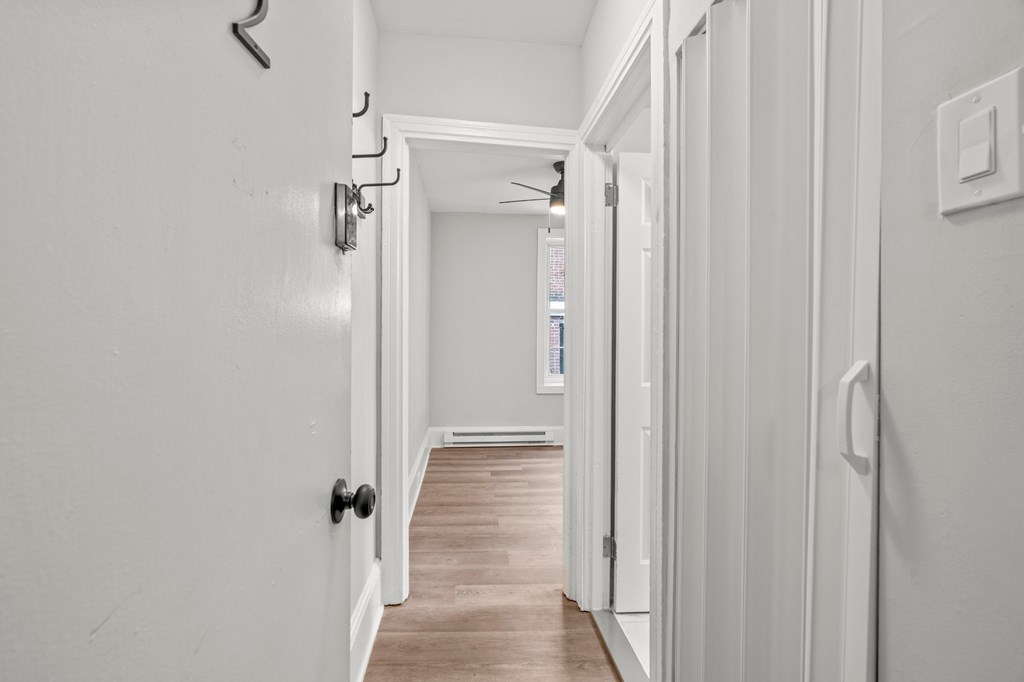 A hallway with white walls and a wooden floor.