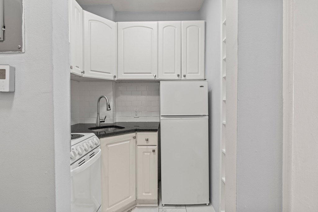 A white kitchen with a stove, oven, and refrigerator.