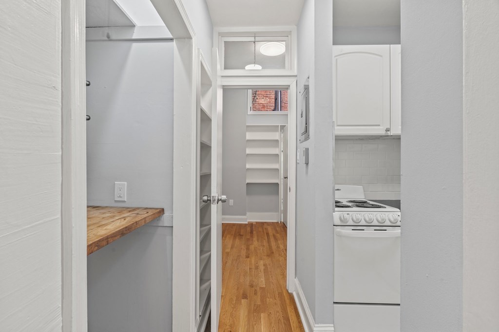 A small kitchen with a white oven and wooden floors.