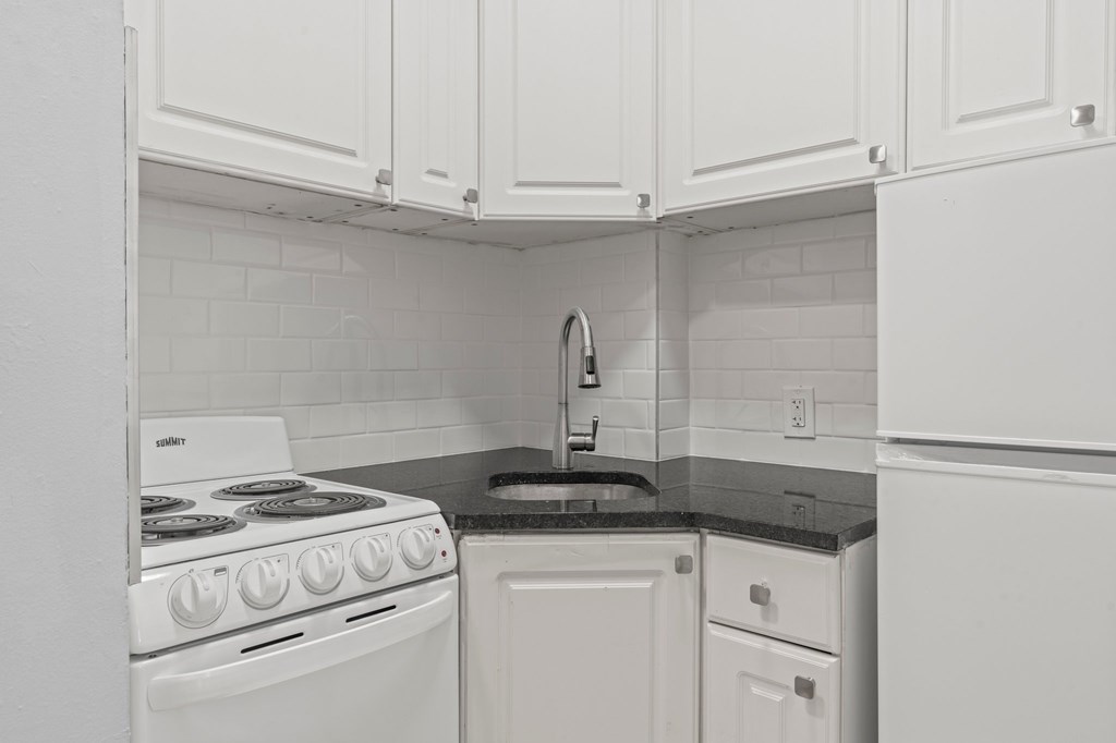 A white stove and oven in a kitchen with white cabinets.