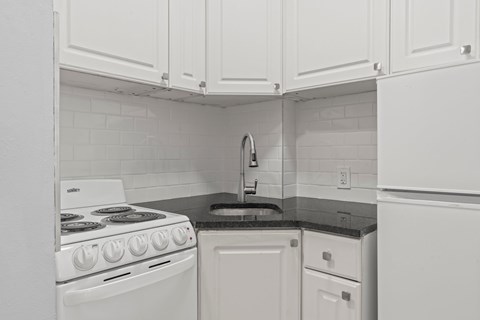 A white stove and oven in a kitchen with white cabinets.