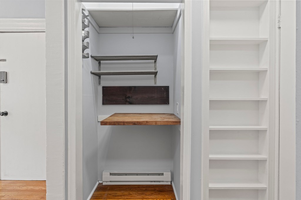 A white pantry with a door open to a white shelving unit.
