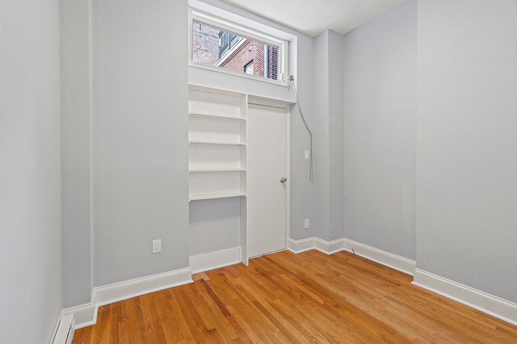 A room with wooden floors and a window with blinds.