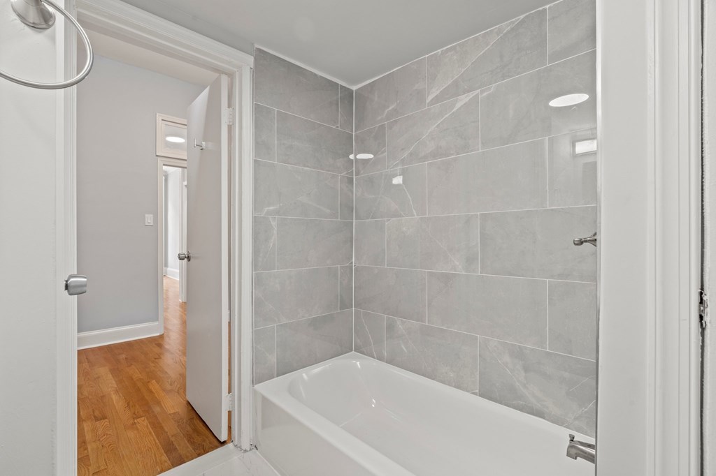 A white bathroom with a tub and tiled walls.