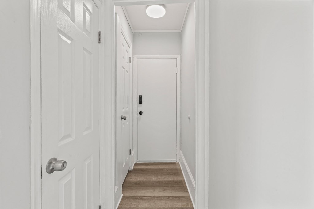 A hallway with a white door and a brown carpet.