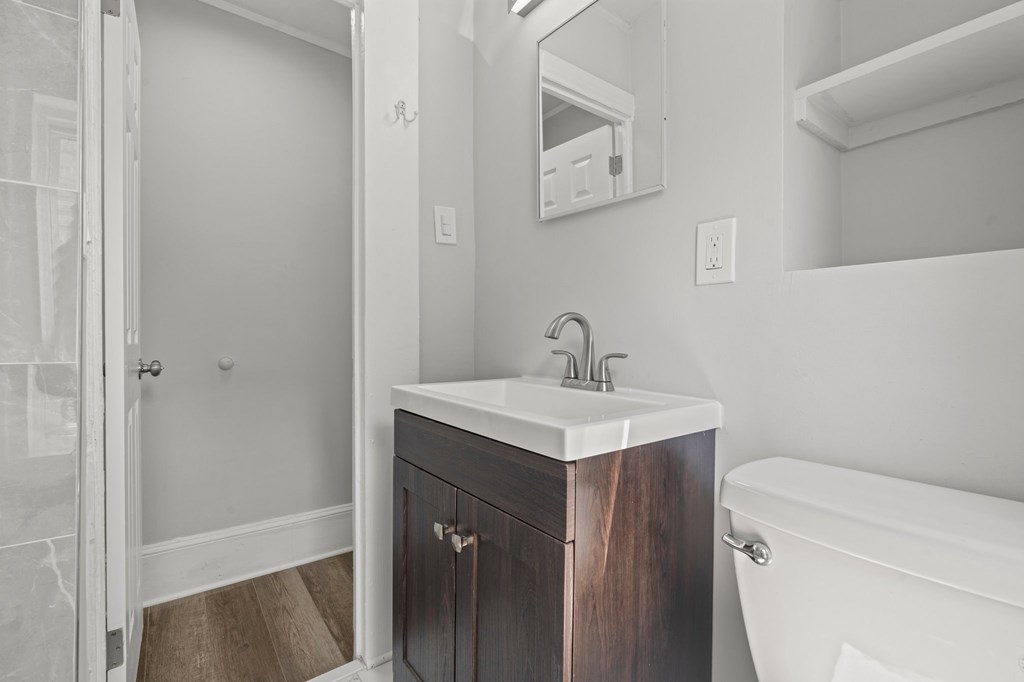 A bathroom with a white tub, sink, and wooden cabinet.